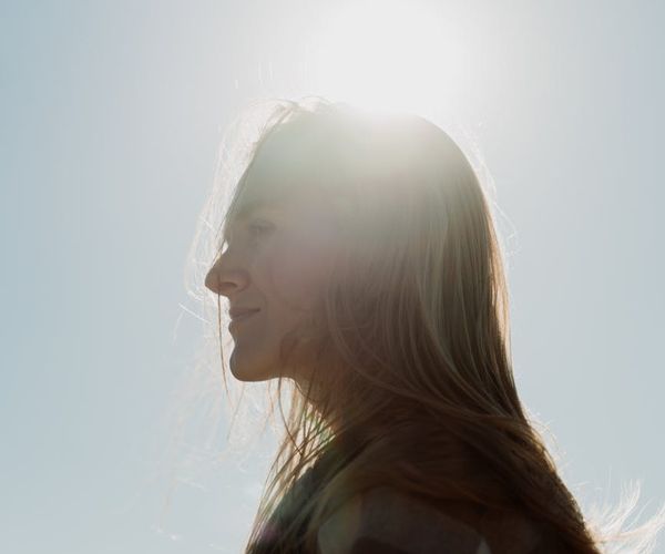 Person meditating peacefully outdoors with a sun halo effect.